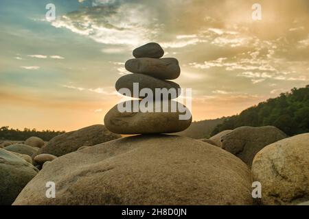 Pietre equilibrate su una spiaggia di ciottoli durante il tramonto in Bangladesh. Foto Stock