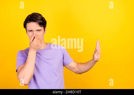 Ritratto di ragazzo attraente che mostra stop segno chiusura naso dissimile isolato su sfondo giallo brillante Foto Stock