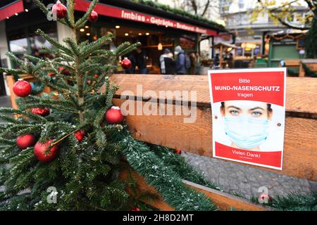 29 novembre 2021, Baviera, Monaco di Baviera: Accanto ad un albero di Natale al Viktualienmarkt è appeso un cartello con l'iscrizione "si prega di indossare la protezione bocca-naso". Foto: Felix Hörhager/dpa Foto Stock