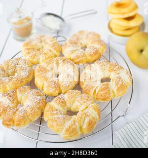 Anelli di mela in pasta sfoglia, con cannella e zucchero in polvere. Foto Stock