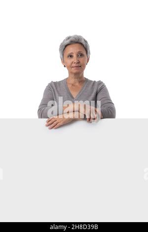 La donna asiatica matura sta tenendo una lavagna di testo vuota su sfondo bianco e mostrando il pollice in su Foto Stock