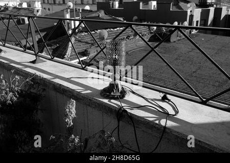 Scatto in scala di grigi di una lampada sulla ringhiera di un tetto durante la luce del giorno Foto Stock