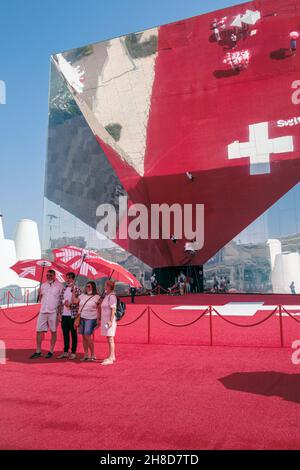 I visitatori hanno avuto ombrelloni rossi da posare all'esterno del Padiglione Svizzero, che era uno specchio gigante che riflette il tappeto rosso, Expo 2020, Dubai, Emirati Arabi Uniti Foto Stock