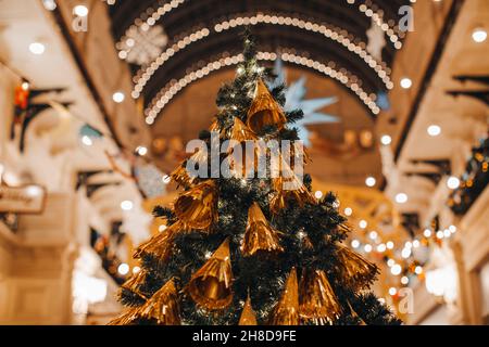 Albero di Natale creativo decorato con giocattoli di Natale d'oro. Atmosfera festosa e decorazioni lucenti all'interno con luci bokeh Foto Stock