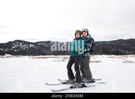 la coppia amorevole si pone per una foto prima di sciare su una pista di montagna innevata. Il giorno di San Valentino, dirigiti verso una località di montagna. Gioia del rapporto. Interesti Foto Stock