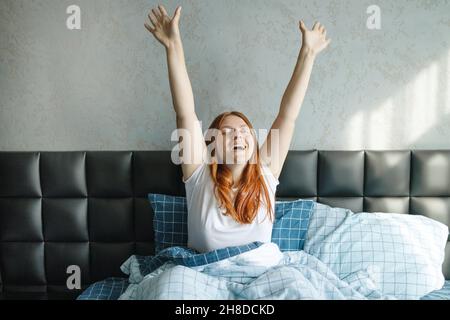 Giovane donna attraente che sbava e stretching in letto confortevole a casa. Sogni dolci, Buongiorno, nuovo giorno, fine settimana, concetto di vacanze Foto Stock