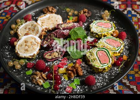 Dolci georgiani con frutta e bacche su piatto nero Foto Stock