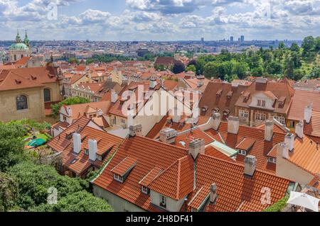 I tetti arancioni di terracotta del quartiere Malá Strana di Praga si estendono oltre la chiesa di San Nicola fino al fiume Moldava e oltre. Foto Stock