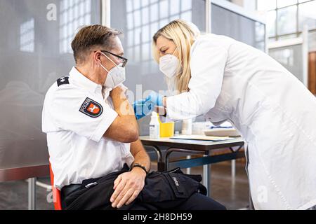 Hannover, Germania. 29 novembre 2021. Un ufficiale di polizia ottiene una vaccinazione di richiamo contro Covid-19. Oggi ad Hannover inizia un'azione concertata per rinnovare lo status di vaccinazione dei dipendenti della polizia della bassa Sassonia. Credit: Moritz Frankenberg/dpa/Alamy Live News Foto Stock