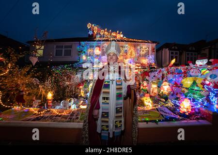 Londra, Regno Unito. 29 novembre 2021. Spettacolare mostra di luci della casa di Natale a Welling. Jonathan Blake (nella foto), Arcivescovo residente della Chiesa episcopale aperta, ha decorato la sua casa di famiglia ogni anno dal 2002. Per alcuni dei bambini locali, "la Casa di Natale" come la chiamano, è una parte vitale della loro esperienza di Natale. Bishop Blake utilizza il display annuale delle luci per aiutare a raccogliere fondi per fornire acqua pulita ai piccoli villaggi in Gambia. Credit: Guy Corbishley/Alamy Live News Foto Stock