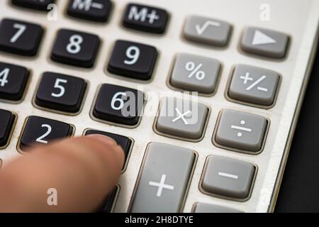 Premere con il dito il calcolatore dei pulsanti. Concetto fiscale, concetto contabile. L'uomo non riconoscibile tiene le mani e usa una calcolatrice Foto Stock