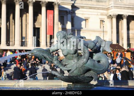 Le fontane su Trafalgar Square con il mercato di Natale fuori dalla National Gallery nel centro di Londra, 2021, Regno Unito Foto Stock