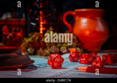 Immagine ravvicinata di un gioco di ruolo a 20 lati rosso muore sullo sfondo di un set di dadi e un vaso in ceramica Foto Stock