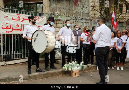 L'associazione Nun insieme alle famiglie delle vittime di Port Blast rende omaggio ai 'giudici onorari' vicino al Palazzo di Giustizia di Beirut, 29 novembre 2021. Un breve concerto e un minuto di silenzio sono stati eseguiti in memoria delle vittime. I dimostranti hanno offerto una rosa bianca a ciascuno dei 21 giudici libanesi che sostengono Tarek Bitar, il giudice responsabile dell'indagine sul porto di Beirut Blast.Tarek Bitar è stato ostacolato molte volte nella sua ricerca della verità sull'incidente, e alcuni giudici lo hanno sostenuto e lo hanno difeso contro minacce e taunts. La bandiera recita: "Una nuova giustizia pulita è Foto Stock