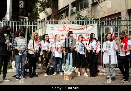 L'associazione Nun insieme alle famiglie delle vittime di Port Blast rende omaggio ai 'giudici onorari' vicino al Palazzo di Giustizia di Beirut, 29 novembre 2021. Un breve concerto e un minuto di silenzio sono stati eseguiti in memoria delle vittime. I dimostranti hanno offerto una rosa bianca a ciascuno dei 21 giudici libanesi che sostengono Tarek Bitar, il giudice responsabile dell'indagine sul porto di Beirut Blast.Tarek Bitar è stato ostacolato molte volte nella sua ricerca della verità sull'incidente, e alcuni giudici lo hanno sostenuto e lo hanno difeso contro minacce e taunts. La bandiera recita: "Una nuova giustizia pulita è Foto Stock