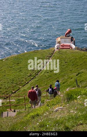 I turisti che camminano verso il corno della nebbia, il Mull of Galloway faro, Dumfries & Galloway, Scozia Foto Stock