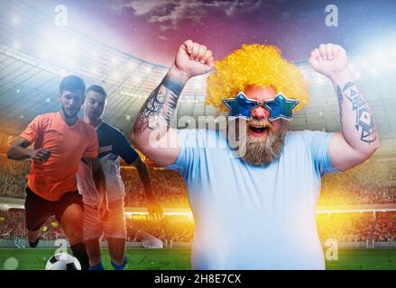 Gli appassionati di calcio esultano a guardare una partita di calcio allo stadio Foto Stock