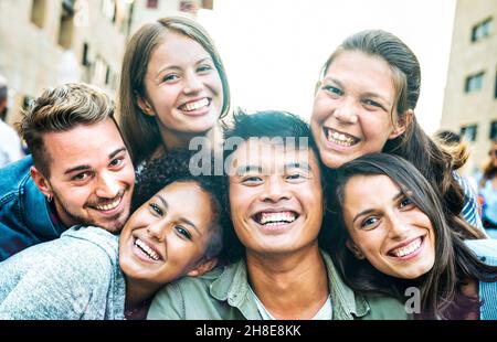 Multiculturale uomini e donne che prendono selfie fuori di lato con retroilluminazione - concetto di stile di vita mileniale felice su giovani amici multirazziale che hanno giorno di divertimento Foto Stock