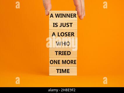 Simbolo del vincitore o del perdente. Blocchi di legno con le parole Un vincitore è giusto un perdente che ha provato ancora una volta. Bellissimo sfondo arancione, spazio copia. Businessma Foto Stock