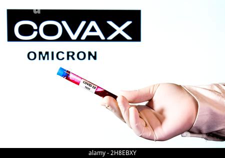 Madrid, Spagna- 29 novembre 2021: Provetta con supporto manuale del virus covid-19 su sfondo bianco con banner di fondazione Covax e parola Omicron scritta o Foto Stock