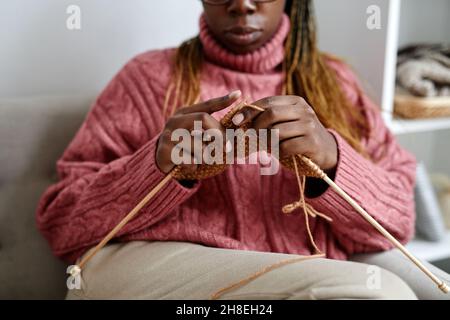 Corto di giovane donna afroamericana che si maglia mentre godendo un week-end accogliente a casa, spazio copia Foto Stock