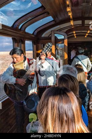 I passeggeri del treno esploratore andino, che corre tra Cusco e Puno, sono intrattenuti nella macchina di osservazione da musicisti e ballerini locali Foto Stock