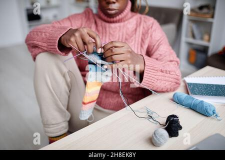 Ritratto corto di giovane donna afroamericana che si mette a maglia a casa in camera accogliente, spazio copia Foto Stock