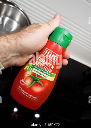 POV maschio a mano con nuovo flacone di plastica con ketchup Felix Foto Stock