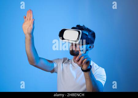 Ritratto dell'uomo in t-shirt nera con occhiali 3d che si gesturano come se tocchasse qualcosa che fa in realtà virtuale durante la riproduzione di video Foto Stock