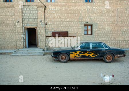 auto con fiamme sul corpo di fronte all'edificio del deserto Foto Stock