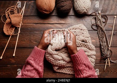 Vista dall'alto primo piano delle mani femminili in maglia su sfondo di legno scuro, spazio copia Foto Stock