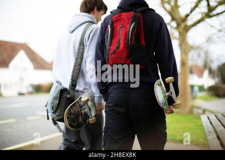 Ragazzi adolescenti con skateboard che camminano sul marciapiede Foto Stock