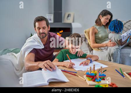 Lettura familiare e disegno in soggiorno Foto Stock