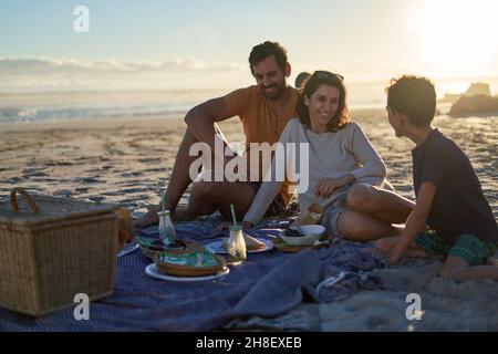 Famiglia felice godersi un pic-nic sulla soleggiata spiaggia estiva Foto Stock