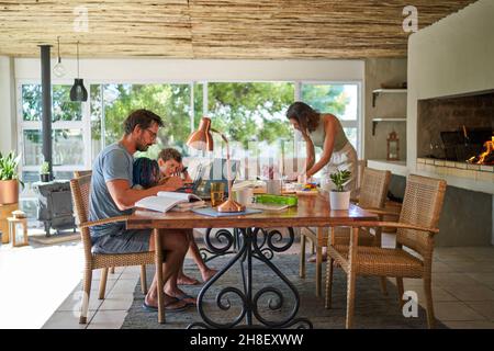 Famiglia che lavora e gioca al tavolo da pranzo Foto Stock Famiglia che lavora e gioca al tavolo da pranzo Foto Stock