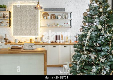 Moderno, leggero, festoso, accogliente cucina interno con decorazioni di  Natale e Capodanno, tavolo da cucina, utensili, padelle in rame a parete e  grande Natale Foto stock - Alamy