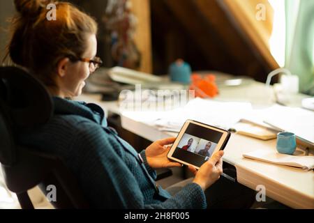 Videoconferenza donna con colleghi sullo schermo del tablet digitale Foto Stock