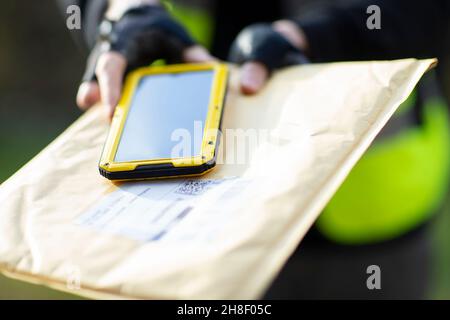 Primo piano corriere con la busta di consegna dello smartphone Foto Stock