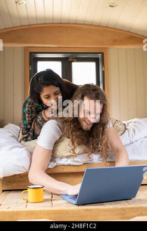 Felice coppia giovane che usa il portatile in una piccola cabina Foto Stock