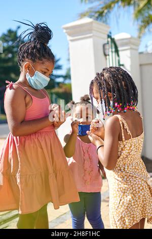 Sorelle carine in maschere di viso in strada soleggiata Foto Stock