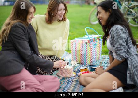 Buone giovani donne amiche festeggiano il compleanno con la torta nel parco Foto Stock