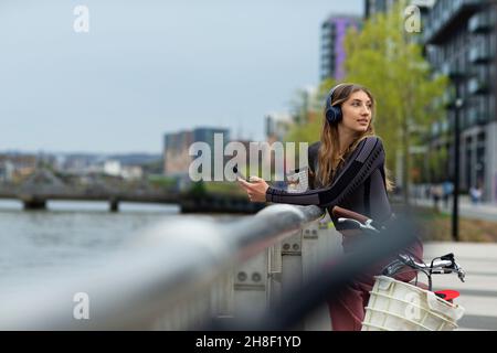 Giovane donna con smartphone sul lungomare della città, Londra, Regno Unito Foto Stock