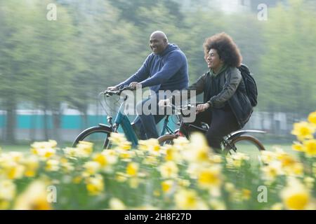 Felice padre e figlio in bicicletta nel parco primaverile Foto Stock