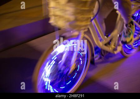 Uomo in bicicletta con luci viola di notte Foto Stock