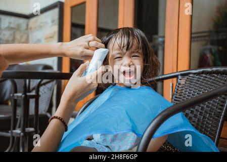 Mamma che ha la figlia un taglio di capelli a casa Foto Stock