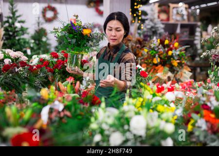 Il venditore di fiori asiatici prepara un bouquet di lusso al negozio di fiori Foto Stock
