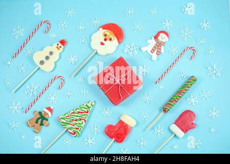 Caramelle di Natale a forma di un pupazzo di neve, albero di natale, babbo natale, Mitten, e mini marshmallows su sfondo grigio. Lollipop, canna di caramelle. Disposizione piatta, vista dall'alto. Spazio di copia Foto Stock