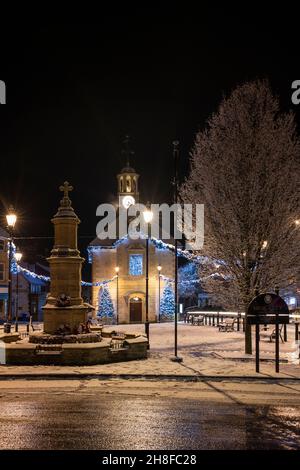 Alberi di Natale e luci fuori dal municipio di brackley nella neve sera. Brackley, Northamptonshire, Inghilterra Foto Stock