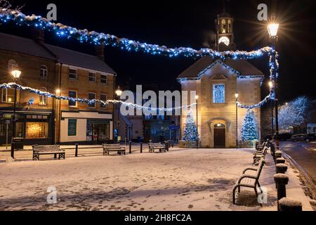 Alberi di Natale e luci fuori dal municipio di brackley nella neve sera. Brackley, Northamptonshire, Inghilterra Foto Stock