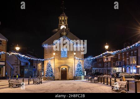 Alberi di Natale e luci fuori dal municipio di brackley nella neve sera. Brackley, Northamptonshire, Inghilterra Foto Stock